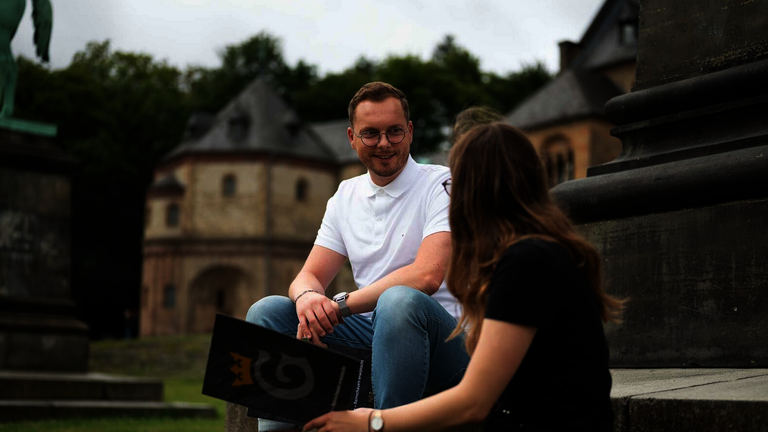 Zwei Personen sitzen vor der Kaiserpfalz und unterhalten sich über Ausbildungsplätze bei der Stadt Goslar