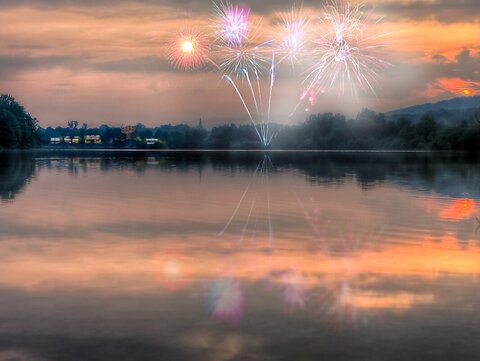 Feuerwerk über einem See bei Sonnenuntergang