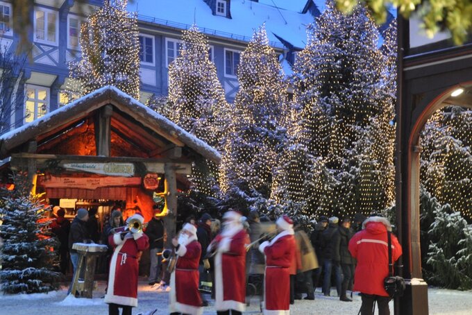 Weihnachtmänner spielen ein Lied mit Instrumenten vom dem Weihnachtswald in der Goslarer Innenstadt vor dem Schuhhof