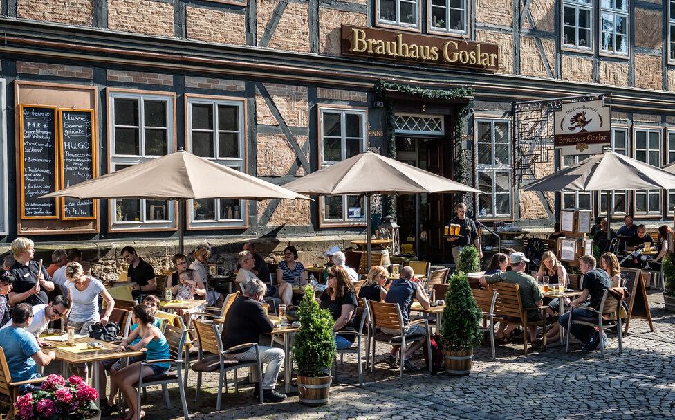 Kundschaft des Goslarer Brauhauses sitzen vor dem Restaurant an Tischen
