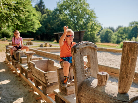 Zwei Kinder sitzen auf einer Holz-Lokomotive auf einem Spielplatz