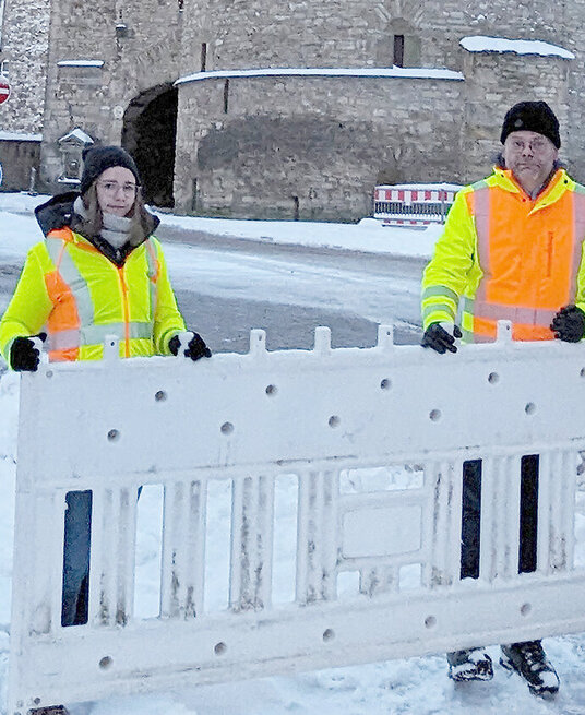 2 Mitarbeiter der Stadt entfernen die Absperrungen vor dem Breiten Tor.