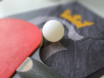 Ein Tischtennisschläger mit einem Ball liegen auf einem Heft mit dem Goslar Logo drauf 